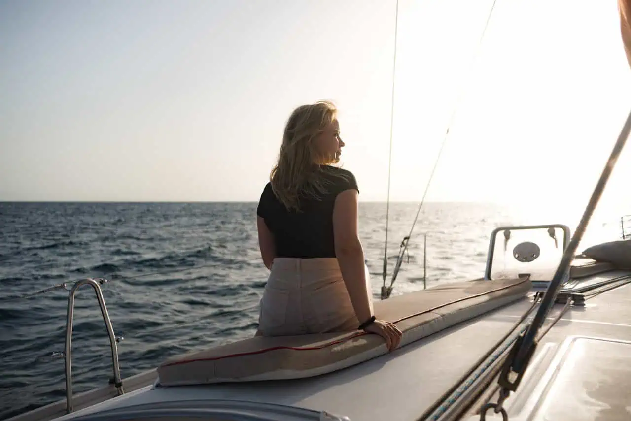 A woman gazes out at the ocean from the bow of the Atlantic Star, embracing the peaceful sea views during a tranquil cruise.