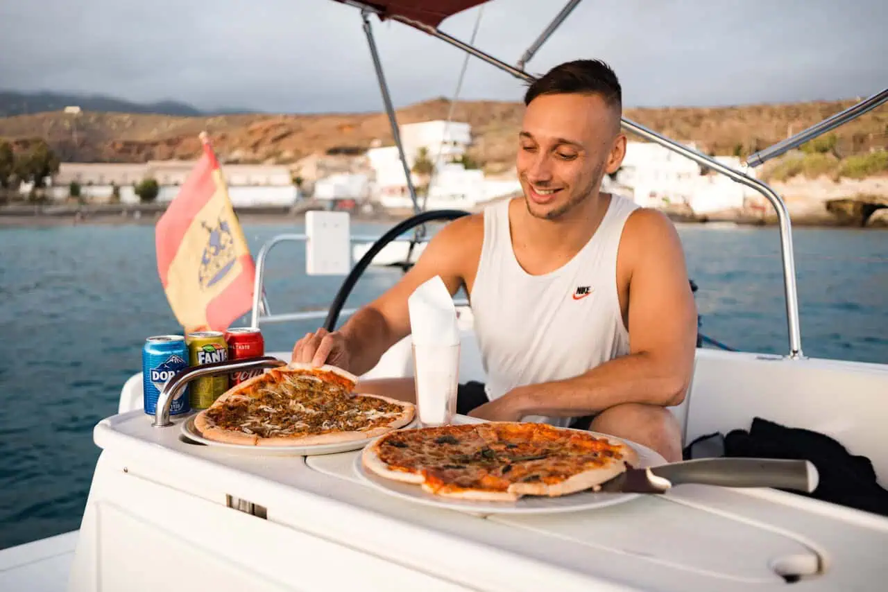 Man serving pizza on a sunset boat cruise off the coast of Tenerife.