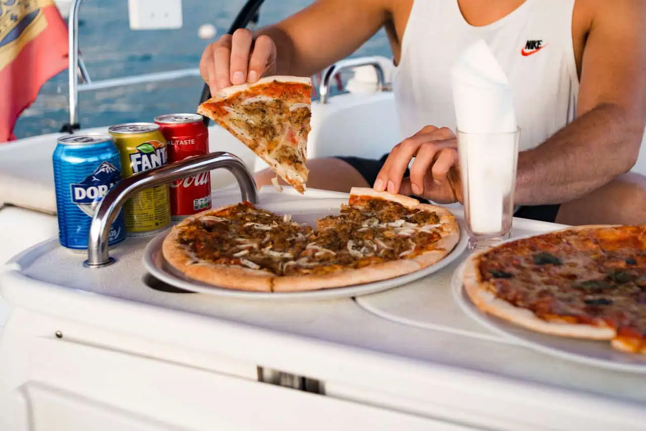 Guests enjoying freshly served pizza and chilled beverages aboard the Atlantic Star, highlighting a casual dining experience at sea.