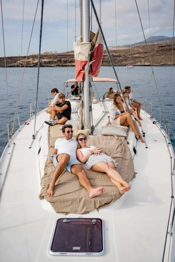 A group of young adults relaxing and sunbathing on the deck of the Atlantic Star yacht during a scenic boat tour around Tenerife's coast, showcasing the leisurely and luxurious experience offered on the tour.